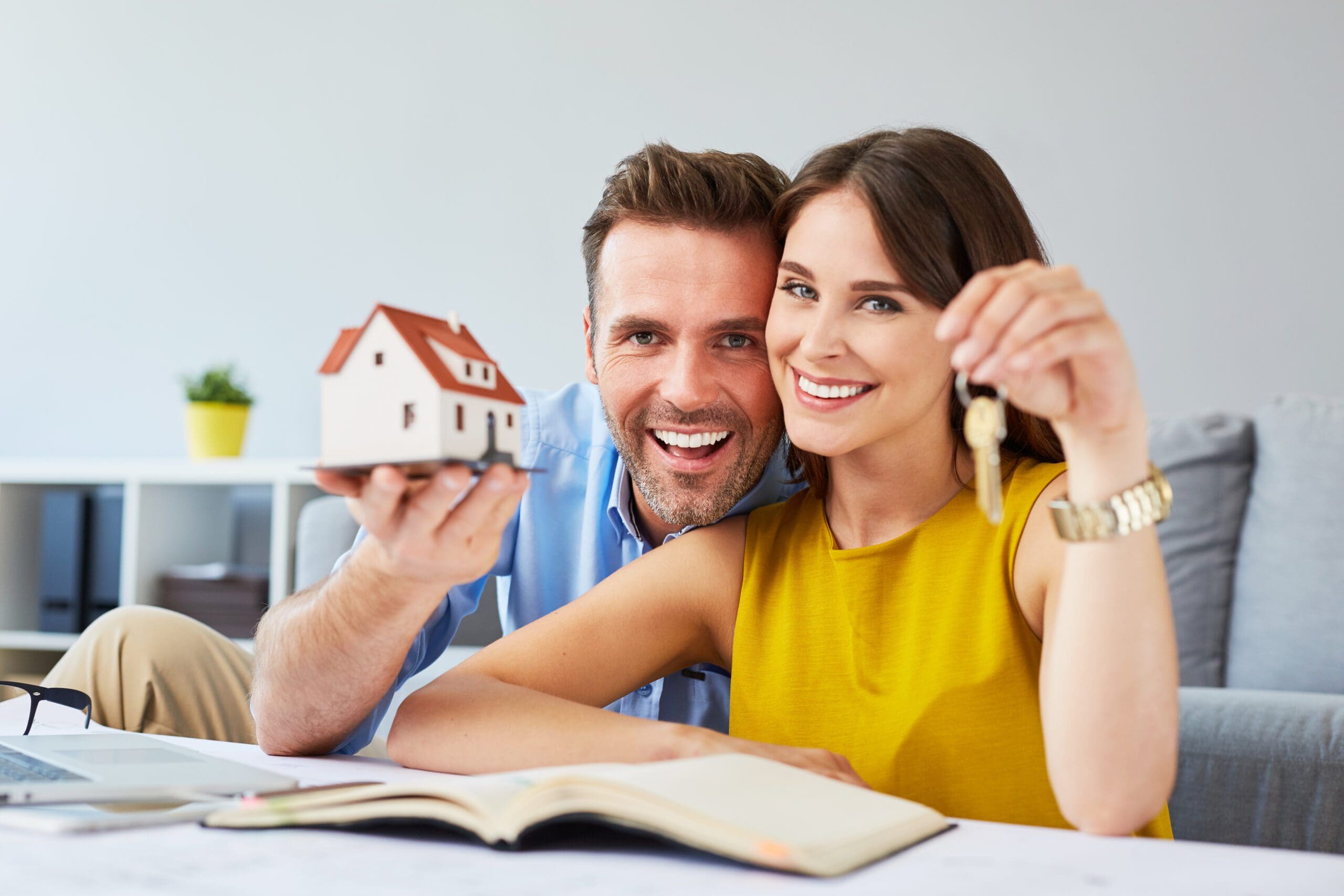 Happy couple holding keys to new home and house miniature Couple with House Keys